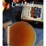 Cocktail in coupe with cinnamon stick, whiskey bottle