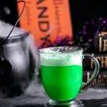 Green cocktail in a mug, Halloween decor in backgroun