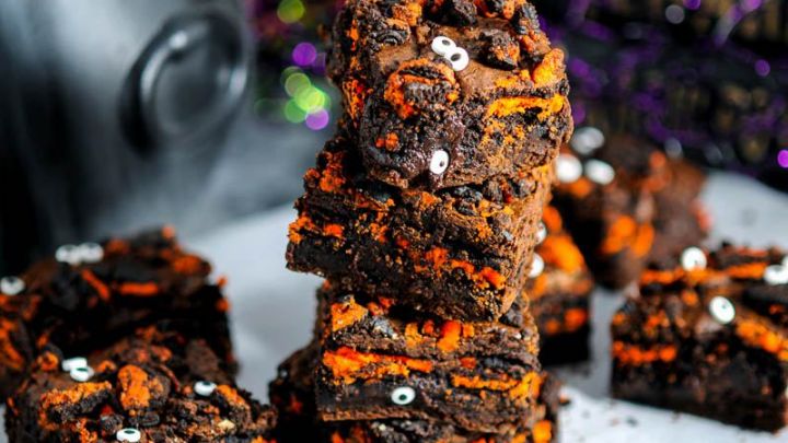 Halloween Oreo Monster Brownies in a stack on parchment paper. Black cauldron behind