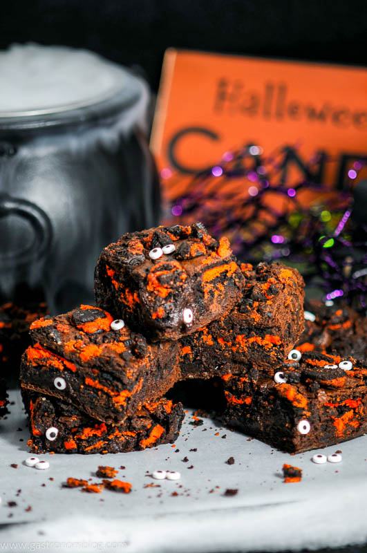 Halloween Oreo Monster Brownies with eyes on parchment paper. Cauldron with dry ice and Halloween sign behind
