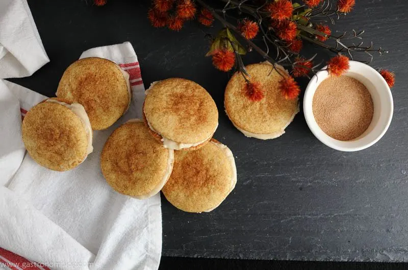 Pumpkin Spice Snickerdoodle Whoopie Pies on slate and white napkin. White ceramic bowl of cinnamon and sugar