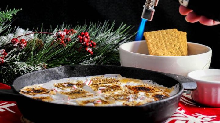 Candy Cane Skillet Smores with Boozy Marshmallows in skillet, white bowl of crackers behind with pine branch