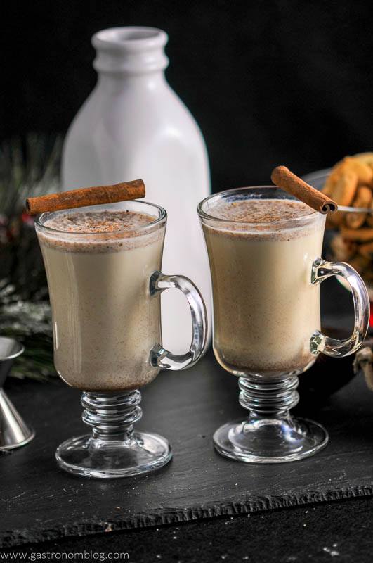 Salted Butterscotch Bourbon Eggnog in glass mugs, cinnamon sticks, milk bottle with cookies in the background