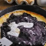 Pancake in cast iron skillet, blackberry sauce and powdered sugar