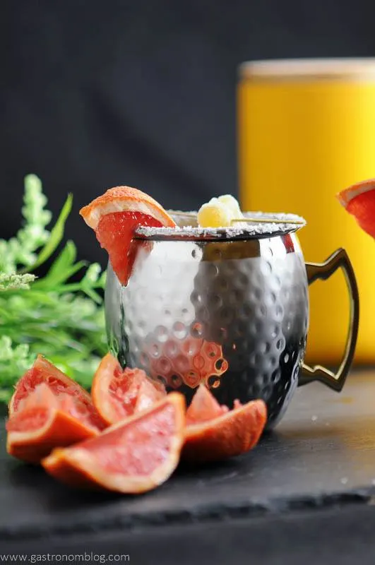 Grapefruit Smoked Salt London Mule in copper mug with grapefruit, flowers and yellow canister