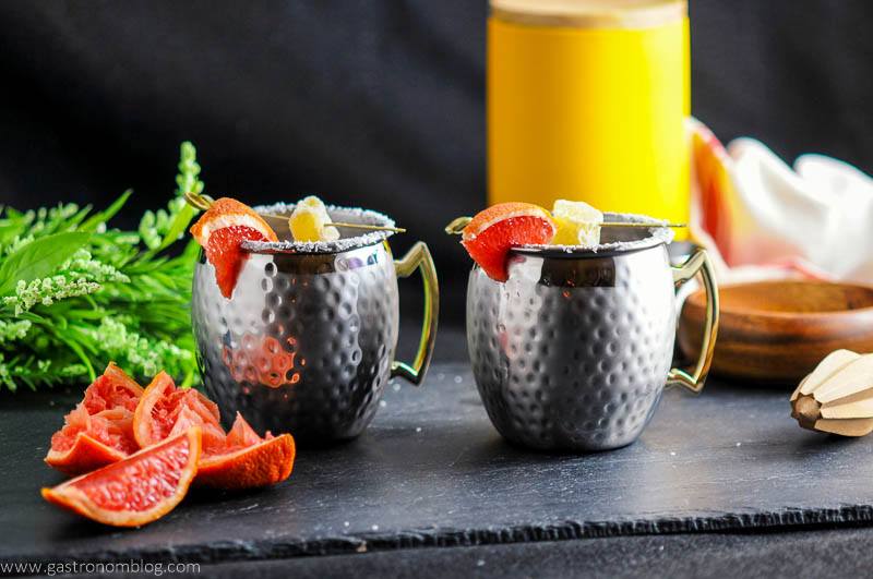 Grapefruit Smoked Salt London Mule in copper mugs, grapefruit wedges with ginger and salt rims. Reamer, flowers, wooden bowl and yellow canister