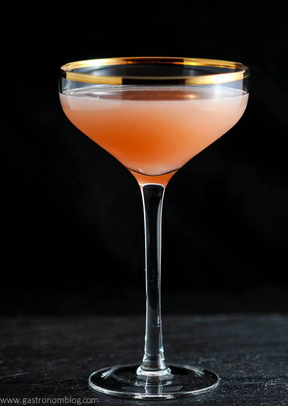 The Pink Pear, pink cocktail in gold rimmed coupe on black background