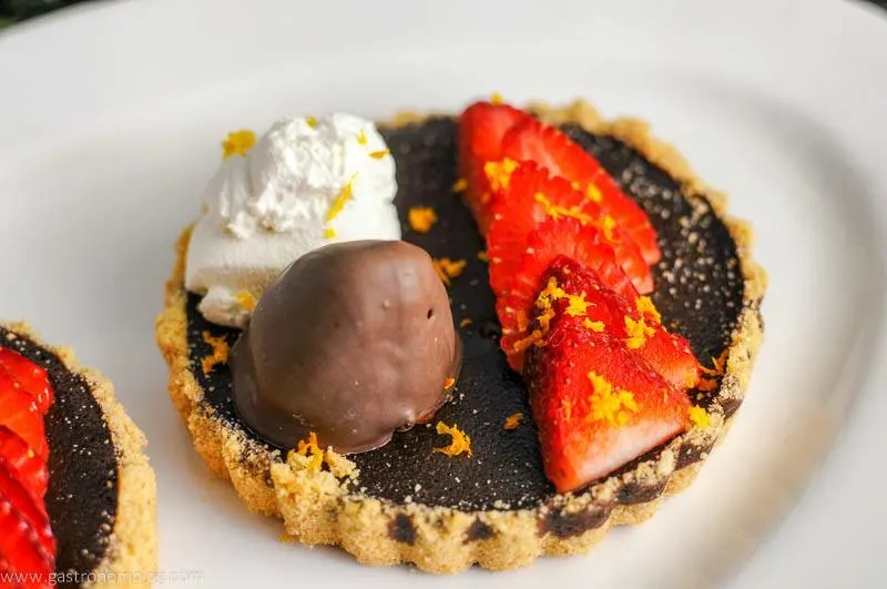 Chocolate Bourbon Tart with Strawberries and whipped cream on white plate