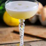 Yellow green cocktail topped with egg white foam
