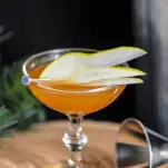 Orange cocktail in coupe with pear slices