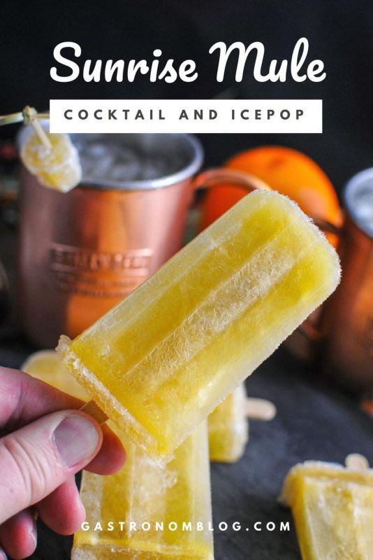 Sunrise Moscow Mule and Popsicles, hand holding popsicle, copper mug with candied ginger, orange in background