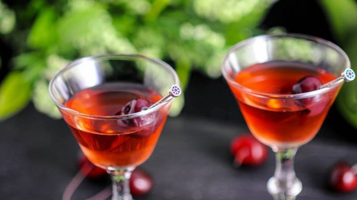 The Cherry Blossom Cocktail, red cocktails in coupes with cherries and greenery
