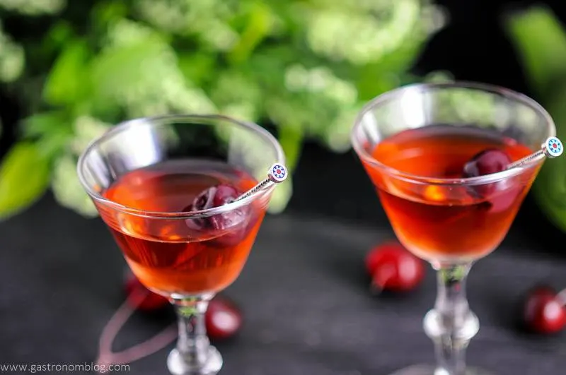 The Cherry Blossom Cocktail in two cocktail coupes with cherries on cocktail picks