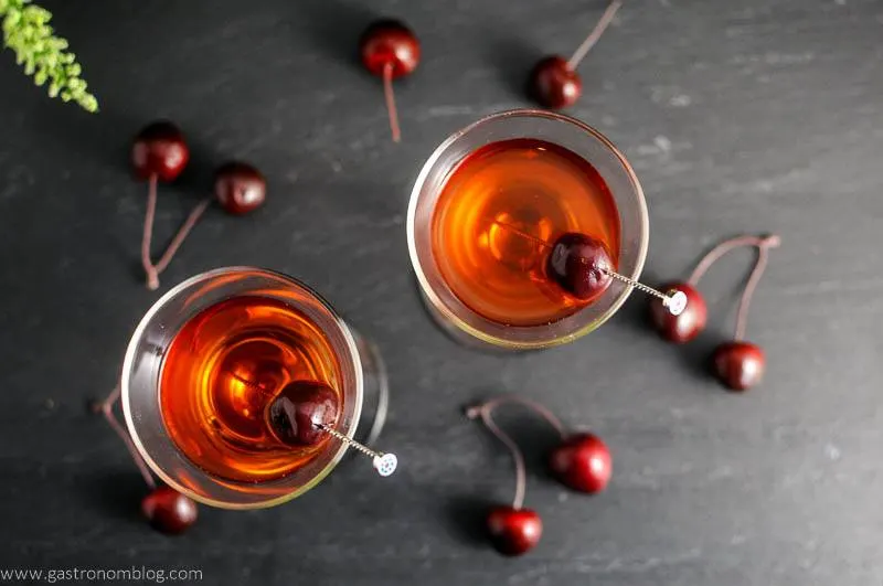 The Cherry Blossom Cocktail in two cocktail coupes with cherries and cocktail picks