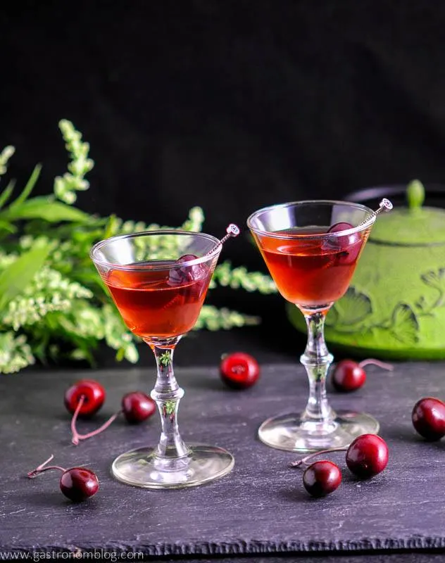 The Cherry Blossom Cocktail, red cocktails in coupes with cherries and flowers behind