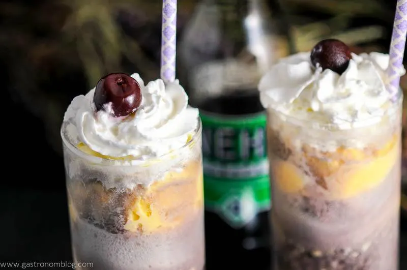 Adult Purple Cow with Nehi Grape Soda in glasses with cherries, whipped cream and straws. Grape soda bottle in background