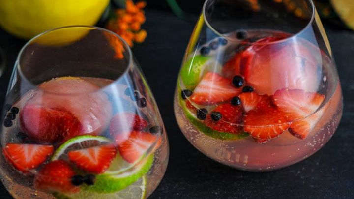 Strawberry Limeade Gin and Tonic Cocktail in glasses with strawberries, limes and juniper berries