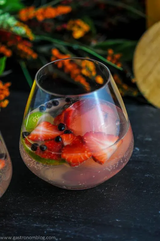 Strawberry Limeade Gin and Tonic Cocktail in glass with flowers in background