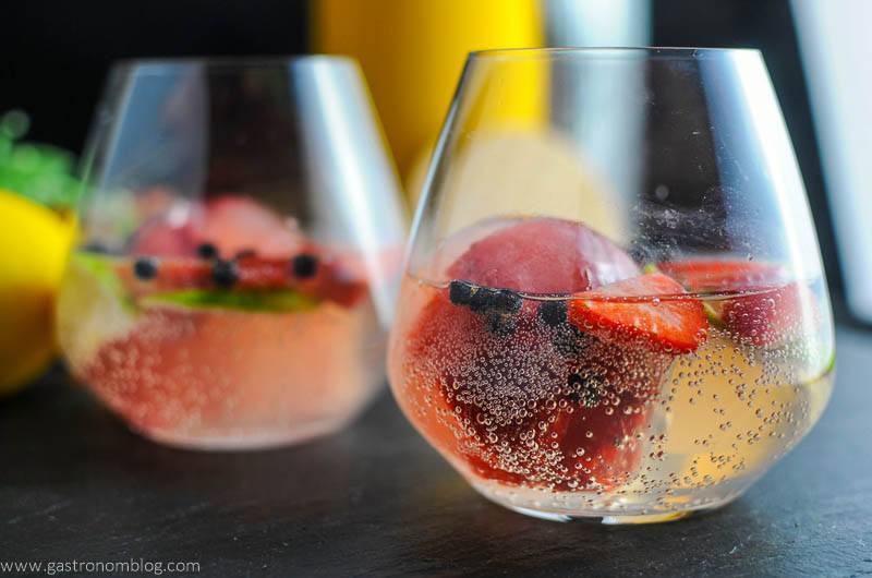 Strawberry Limeade Gin and Tonic Cocktails in glasses with strawberries, limes and juniper berries