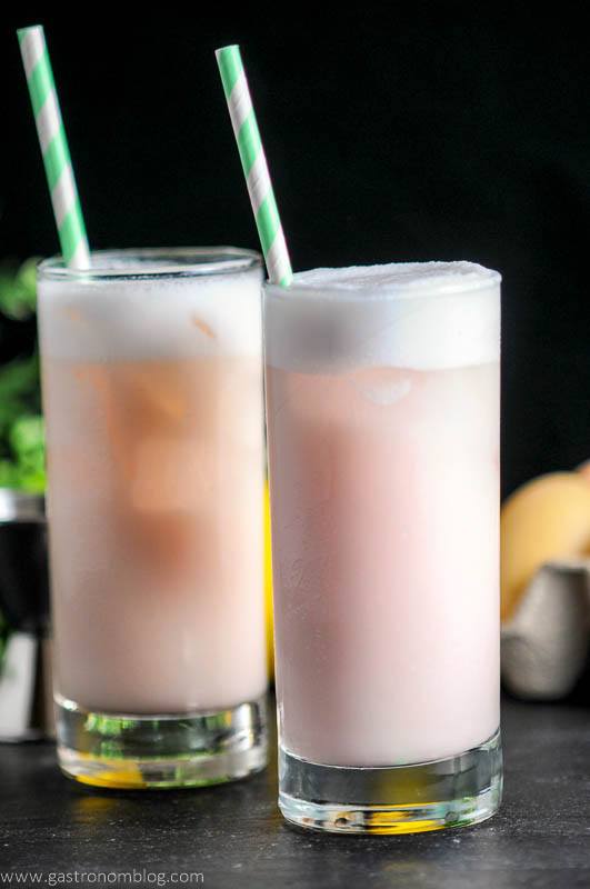 Raspberry Peach Ramos Gin Fizz, pink cocktails with white foam in highballs. Green straws