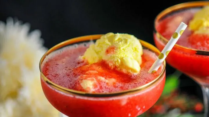 Strawberry Rhubarb Daiquiri Float, red cocktails with ice cream in gold rimmed coupes, gold dot straws. White flowers in background