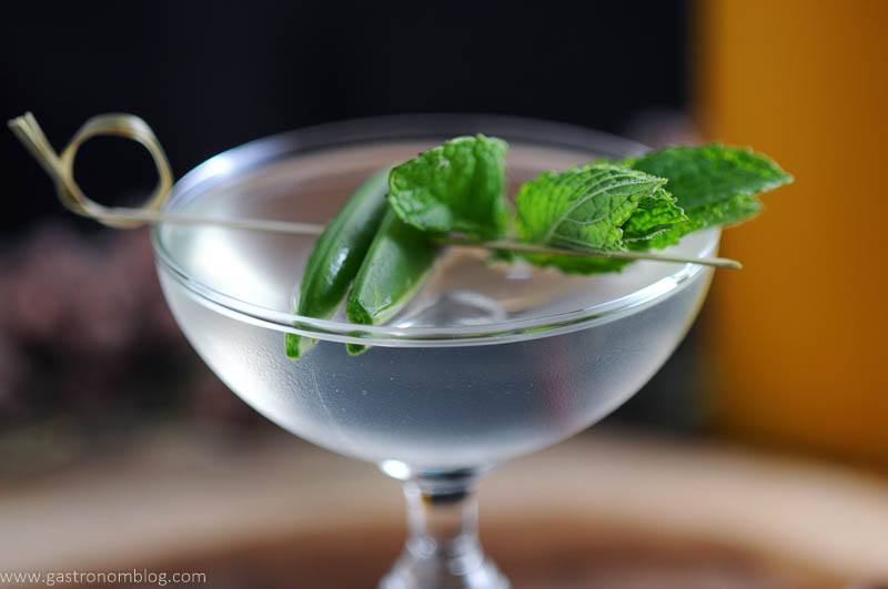 The Spring is Here cocktail with mint and peas on cocktail pick in coupe