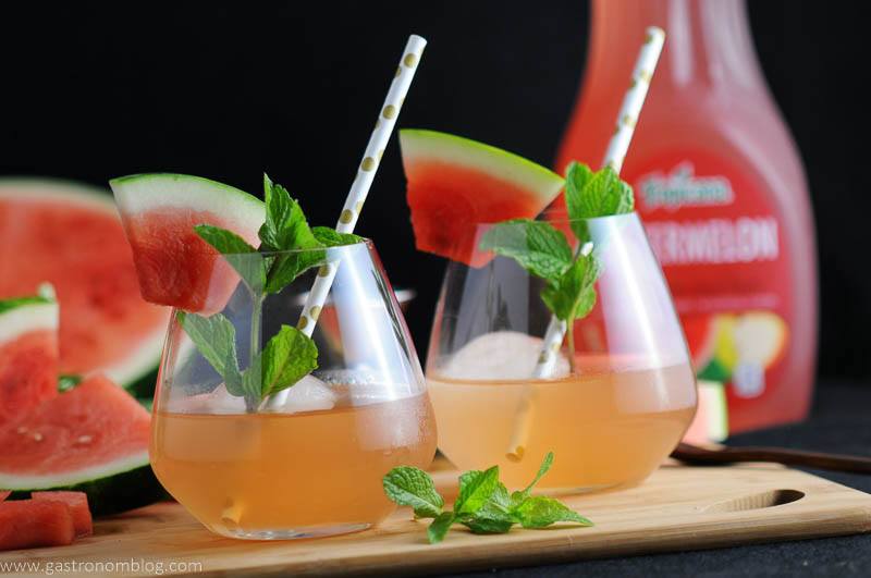 cocktails. Gold dot straws, watermelon wedges and mint sprigs. Watermelon slices and Tropicana watermelon juice bottle in background