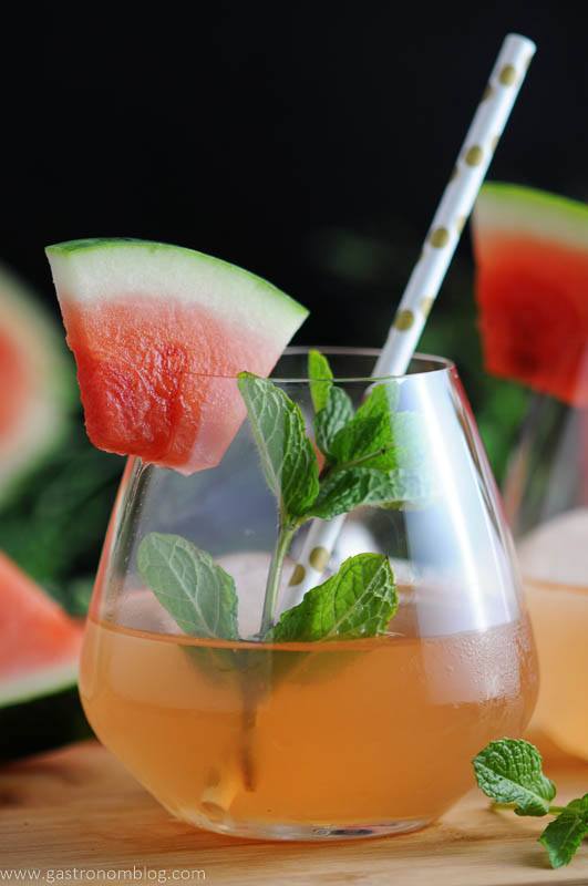 Watermelon Bourbon Cooler, pink cocktail in glass with mint, watermlon slice and dot straw