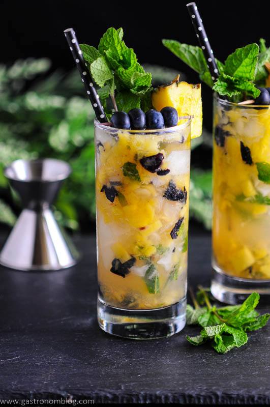Pineapple and bluberries in glasses with straws and mint