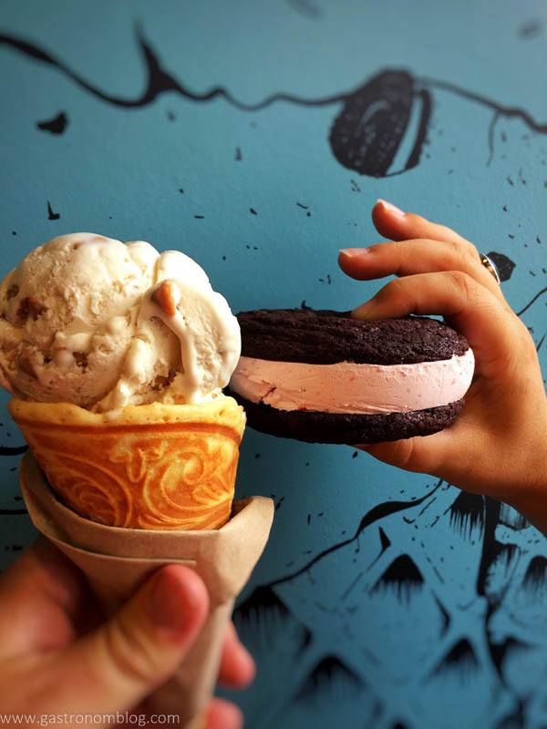 Ice cream in cone and chocolate ice cream sandwich against blue wall
