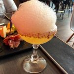 Yellow cocktail in coupe with salt rim and pink foam on top