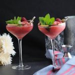 Watermelon Raspberry Frosé, pink cocktails in gold rimmed coupes, mint leaves. Blue napkin, flowers and metal container in background