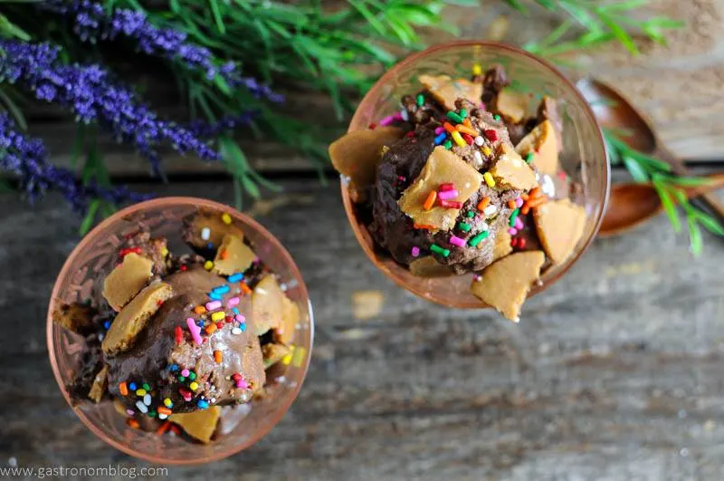 Dark Chocolate Vegan Ice Cream with Rum and No Bake Gluten Free Rainbow Sprinkle Cookie Crumble in pink glass dishes with flowers and wooden spoons