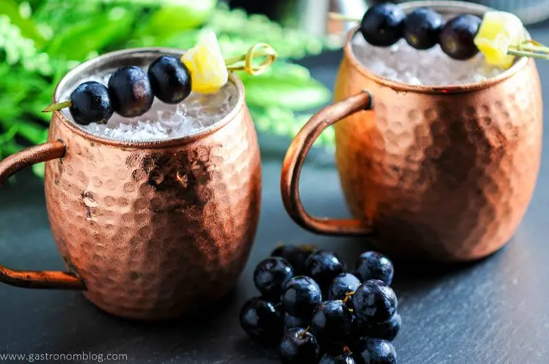Concord Grape Moscow Mule in mugs with grapes and ginger. 