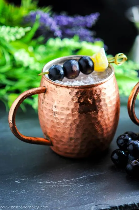 Concord Grape Moscow Mule in copper mug with grapes, greenery in background