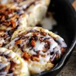 Bourbon Bacon Cinnamon Rolls topped with bacon and in skillet