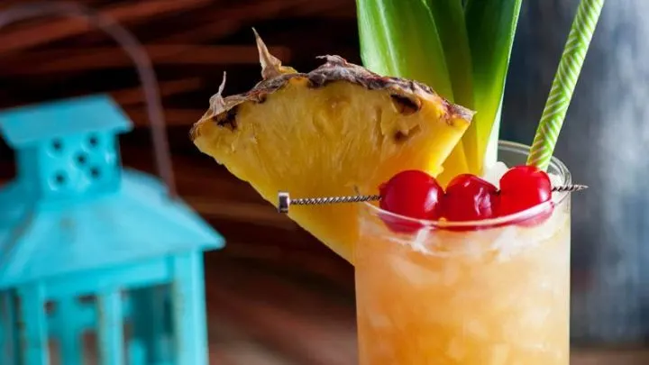 The Fall in Paradise Cocktail garnished with cherries, pineapple wedge and pineapple leaves.