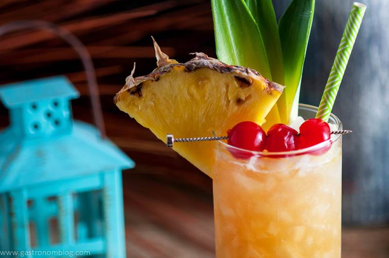 The Fall in Paradise Cocktail garnished with cherries, pineapple wedge and pineapple leaves.