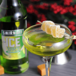 Green cocktail in coupe with candied ginger and bottles