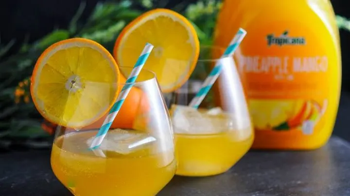 A pair of Tropical Rum Punch cocktails made with Tropicana Pineapple Mango with Lime Premium Juice Drink