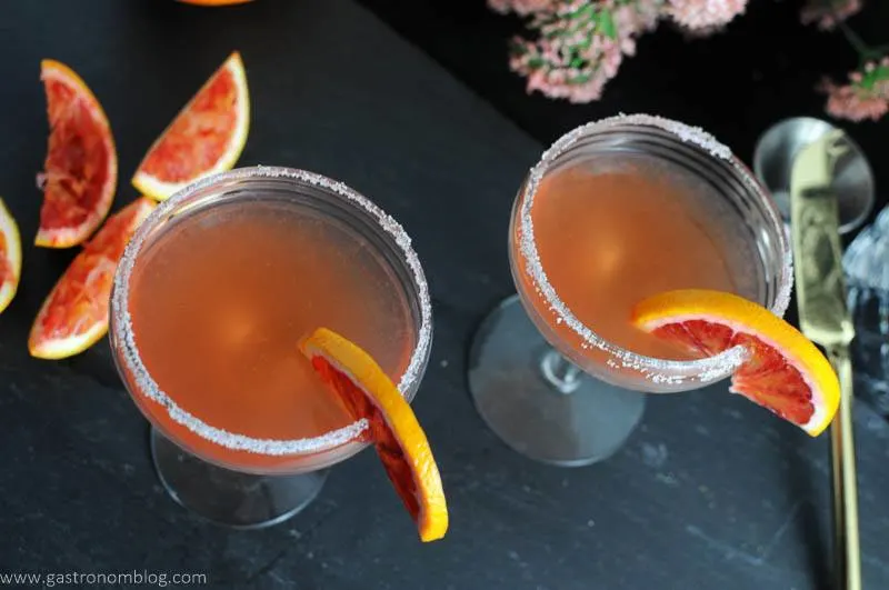 Top shot of a pair of blood orange sidecar cocktails, blood orange slices on glass rims