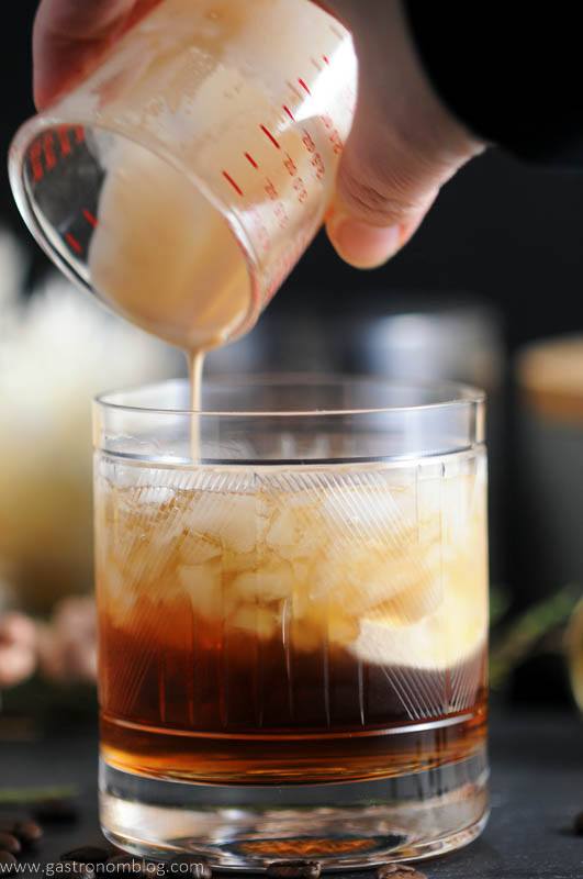 Toasted cream is poured into a rocks glass containing a mixture of Kahlua, vodka and chai tea simple syrup, making a Chai Toasted Cream White Russian Cocktail.