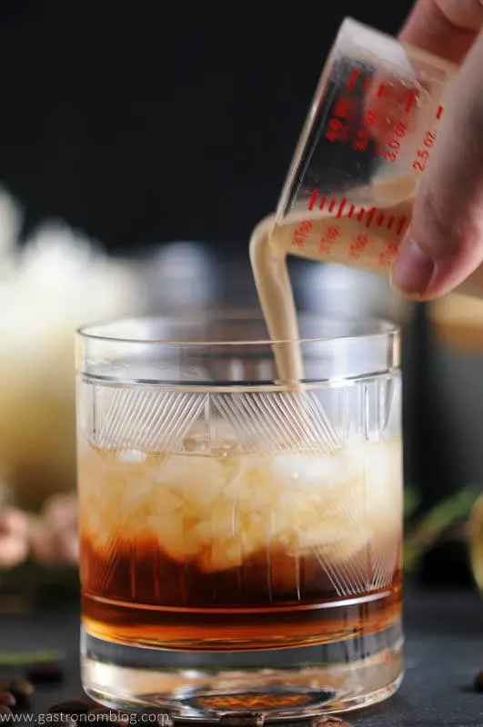Toasted cream is poured into a rocks glass containing a mixture of Kahlua, vodka and chai tea simple syrup, making a Chai Toasted Cream White Russian Cocktail.