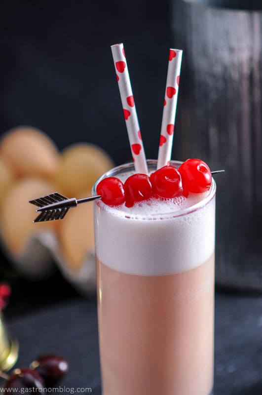 an arrow cocktail pick pieces maraschino cherries that garnish a Cherry Toasted Cream Ramos Gin Fizz