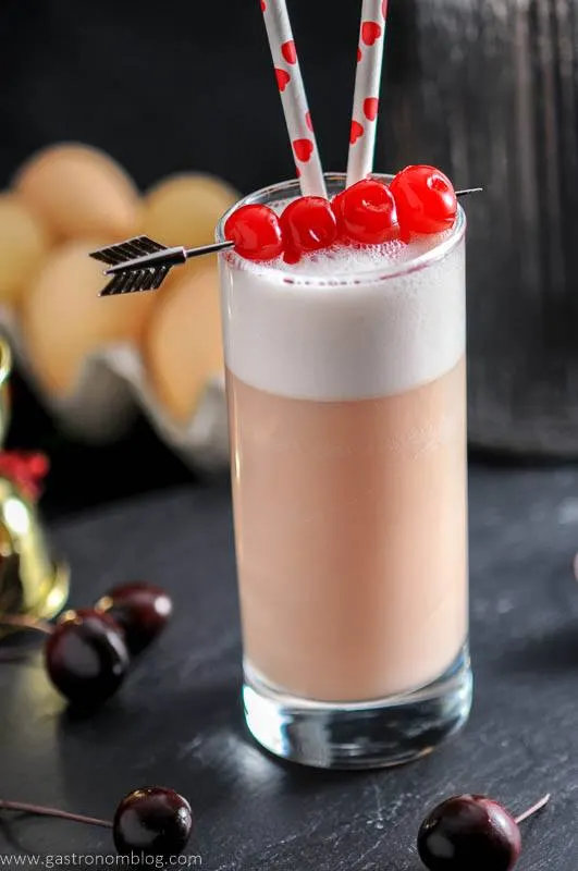 Maraschino cherries top a highball glass filled with a Cherry Toasted Cream Ramos Gin Fizz.