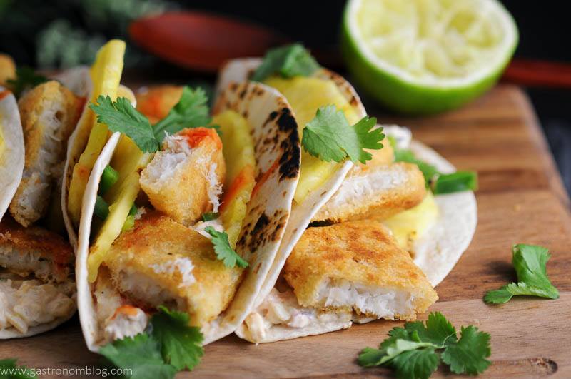 Pub Style Breaded Cod fills these spicy fish tacos with Rum Soaked pineapple, topped with cilantro and hot sauce.