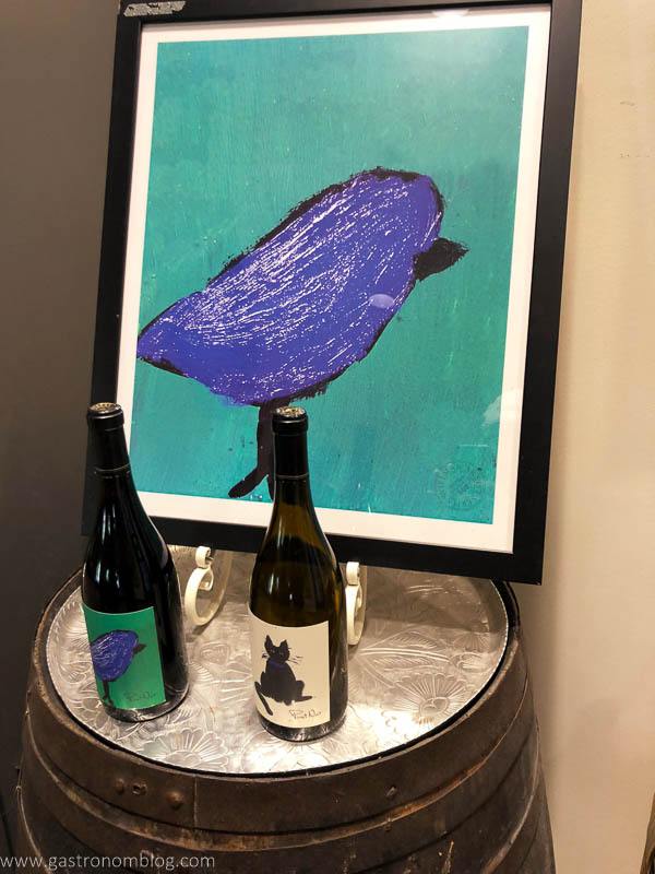 Picture of a bluebird on wine barrel. Wine bottles on top
