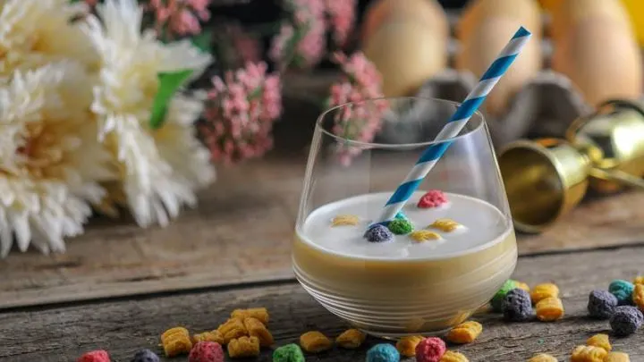 Cocktail with straw, cereal around, flowers and eggs behind