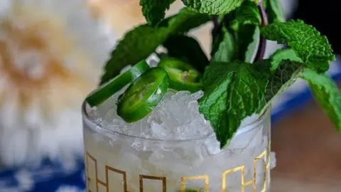 The Mexican Mint Julep is a mezcal cocktail served in a rocks glass and topped with jalepeno and fresh mint.