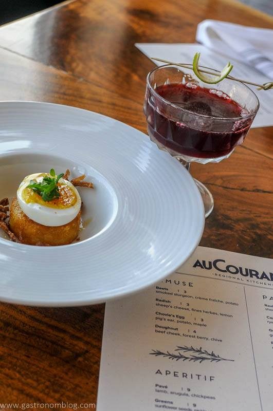 Egg and food on white plate, purple cocktail in coupe at Au Courant in Omaha, Nebraska